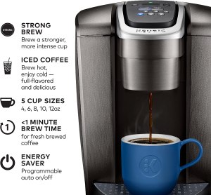 A Keurig K-Elite Single Serve Coffee Maker with a cup of coffee and a spoon on a wooden table.